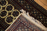 Hand-knotted vintage Bokhara rug pile with elephant footprint guls, tight woven back, and fringe.
