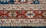 Intricate floral arabesques in the brick red and sky blue border of the vintage hand-knotted carpet.