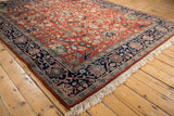 Vintage Indian Bijar rug with rust field, navy blue border, floral elements, and white fringe.