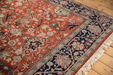 Vintage Bijar rug corner with rust field, navy border, scrolling floral motifs, and fringe.