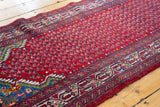 Angled view of the intricate boteh pattern and wave border on a vintage Tajabad runner.