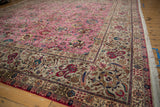 Corner view of a vintage Tabriz carpet highlighting the detailed silver border against the pink floral field.