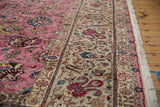 A vintage Tabriz carpet's silver floral border shown beside the pink field and original fringe.