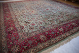 Corner of a vintage Tabriz carpet showing its raspberry red border and powder blue field with prancing deer.