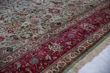A vintage Tabriz carpet corner contrasts a raspberry red border with a dusty blue pictorial field.