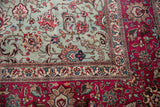 Corner of a vintage Tabriz carpet showing a leopard on the dusty blue field and a raspberry red floral border.