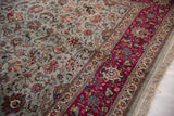 Detail of a vintage Tabriz corner showing the raspberry red border against the dusty blue forest theme field.