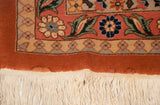 Close-up of the vintage carpet's corner, detailing the floral border, ivory fringe, and minor repiling.
