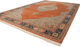 Angled perspective of a vintage Tabriz carpet, showing its intricate navy border, silver field, and orange medallion.