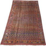 Angled view of a large antique Afshar carpet with its dense boteh pattern and intricate cartouche borders.