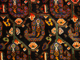 Detail of the intricate boteh pattern in sapphire, orange, and saffron on an antique Afshar rug's navy field.