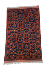 Angled view of a vintage Taghan rug showing the paneled tree of life pattern in chestnut and indigo.