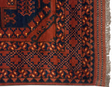 Chestnut brown Ersari rug corner with navy geometric lattice border and kilim selvage.