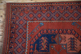 Geometric lattice border in navy blue and madder red on a vintage hand-knotted Ersari rug corner.