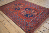 Angled profile of a vintage Pakistani Ersari rug showing its madder red field and geometric motifs.