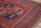Angled corner view of a vintage Ersari rug showing its geometric diamond lattice border and plush pile.