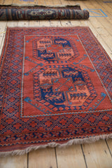 Low angle view of a vintage Pakistani rug, highlighting the plush madder red pile and geometric gul design.