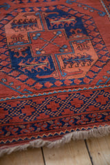 Corner of a vintage Ersari rug with a navy geometric border, full pile, and natural fringe.