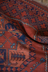 The plush, full pile of a hand-knotted Ersari rug in madder red with a navy lattice border.