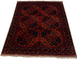 Full angled view of a vintage Ersari rug with bold gul motifs in madder red and navy blue.