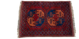 Angled view of a vintage Ersari rug, showing its plush brick red pile and geometric motifs.