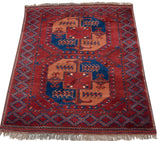Angled view of a vintage Pakistani Ersari rug showing the full geometric pattern and plush red pile.