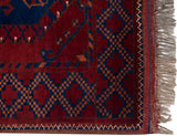 Corner detail of the vintage rug's geometric border, intact side cord selvage, and wool fringe.