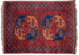 Geometric elephant footprint guls in sapphire blue and apricot on a brick red vintage Ersari rug.