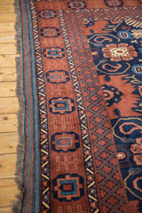 Fringed side cord selvage and geometric borders of the vintage Taghan carpet in copper and navy.