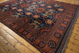 Corner view of the vintage Taghan rug with fringe, copper and navy geometric border, and floral motifs.