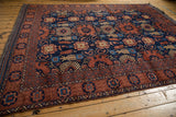 Intricate geometric border and field motifs in copper and navy on the Taghan rug.