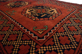 Detail of a vintage Ersari rug, featuring chestnut field, navy geometric guls, and zigzag border.