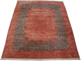 Vintage Kerman carpet viewed from an angle, showing the plush dusty rose pile and scrolling vine border.