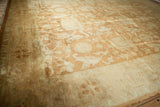 Angled view showing the lustrous gold field and sea foam green border of an Oushak carpet.