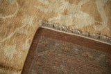 Back of a hand knotted carpet corner showing the weave, secured fringe, and soft gold pile.