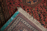 Folded Vintage Abadeh rug corner, showing dusty blush field, fringe, and turquoise bound foundation.