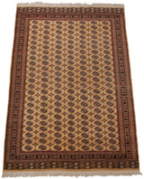 Vintage Bokhara carpet from an angle, displaying repeating geometric guls on a pale gold field.