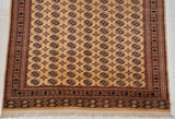 A view of the clean ivory fringe below the detailed geometric end border of a vintage Bokhara carpet.
