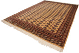 Full length angled view of a vintage Bokhara carpet with repeating guls on a pale gold field.