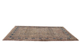 An antique Persian Kermanshah carpet viewed from a low angle, emphasizing its grand size and navy cartouche border.