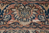 Detail of a main border cartouche showing hand-knotted pile in dusty copper and navy blue.