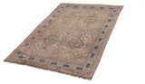 Angled view of a large antique Kermanshah carpet with an ivory field and prominent navy border cartouches.