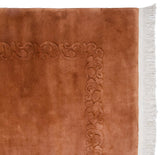 Art Deco carpet corner with dimensional copper foliage carving, plush pile, and white fringe.