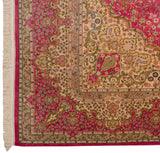 The detailed corner and floral borders of a vintage Kerman rug in pink, ivory, and seafoam green.