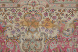 The carpet's hand-knotted millefleur field with delicate vinery in pink, blue, and dusty gold.