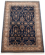 Angled perspective on a vintage Sarouk carpet's sprawling navy field and ivory floral borders.