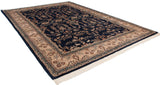 A hand-knotted Mohajeran Sarouk carpet shown at an angle, displaying its navy field and sprawling floral motif.