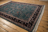 Angled view of the vintage Sarouk carpet's plush teal pile and sprawling floral details.