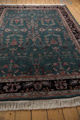 Low-angle view showing the plush, full pile and crisp fringe of a vintage teal Sarouk design carpet.