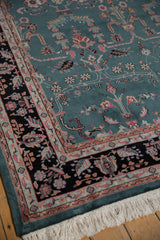 Full teal pile, black floral border, and clean white fringe on a vintage Indian carpet's corner.